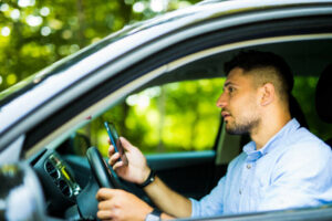 Man driving and looking at his phone