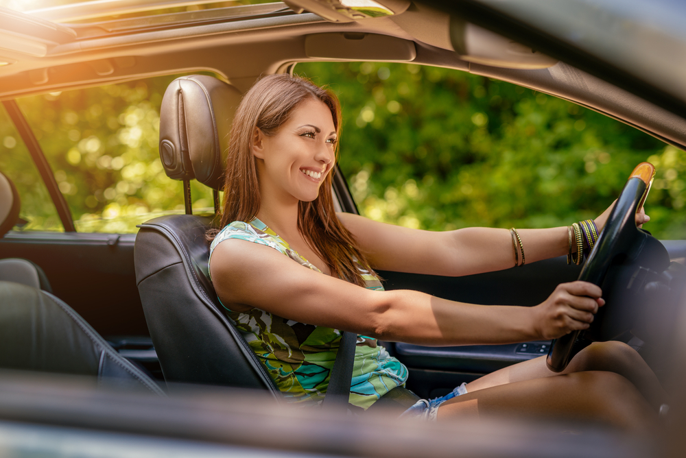 Young-beautiful-woman-smiling-while-driving-a-car