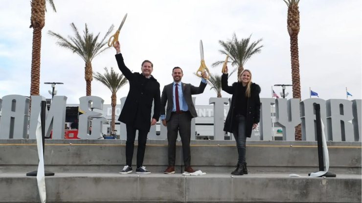 sam and ash with large scissors at a grand opening