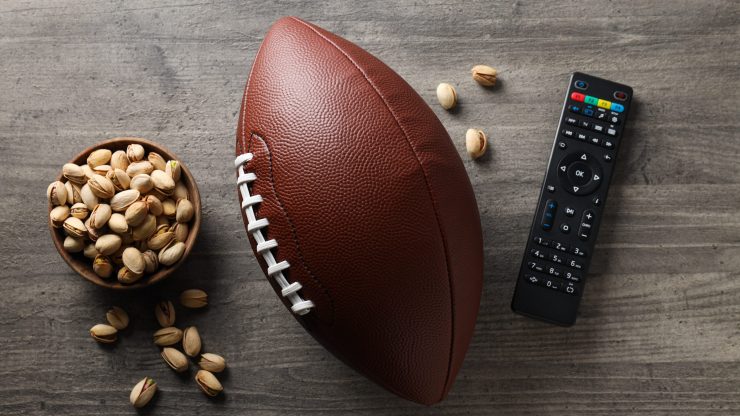 A football, remote, and bowl of pistachios create a relaxed, inviting atmosphere for game day.