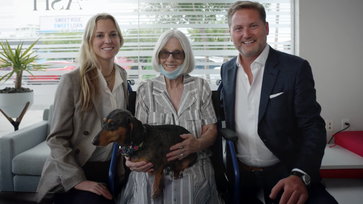 A caring team poses confidently with a client and her dog, reflecting support and compassion.