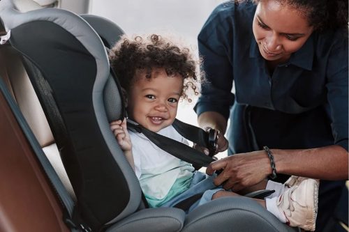 woman buckling her baby in his carseat