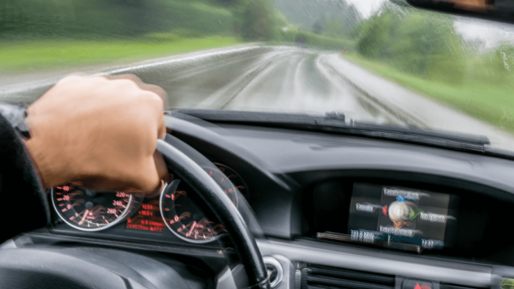 A focused driver navigates a rainy road, embodying determination and safety on the journey ahead.