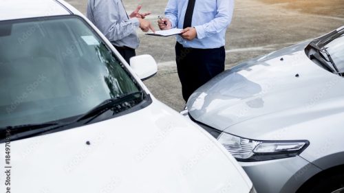 two people standing in front of their car accident exchanging insurance info