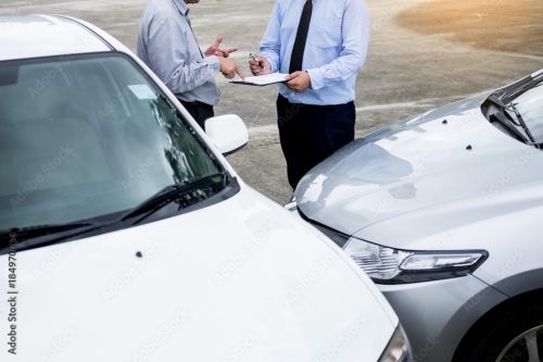 two people standing in front of their car accident exchanging insurance info