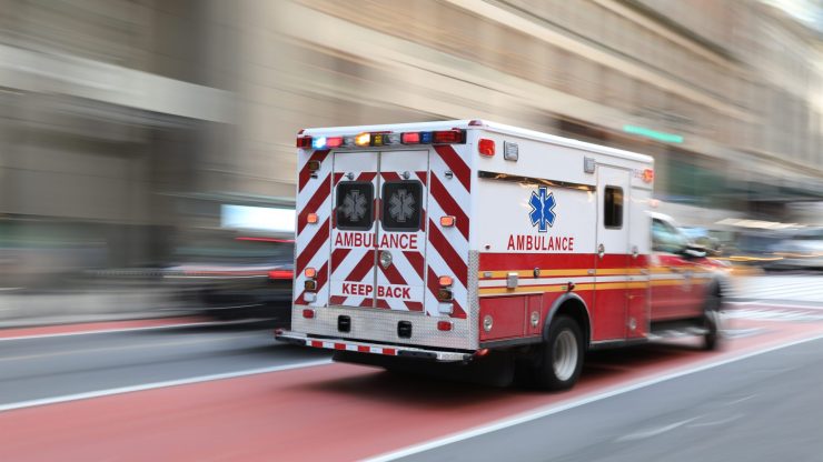 An ambulance speeds through a bustling city, symbolizing urgent care and support in emergencies.