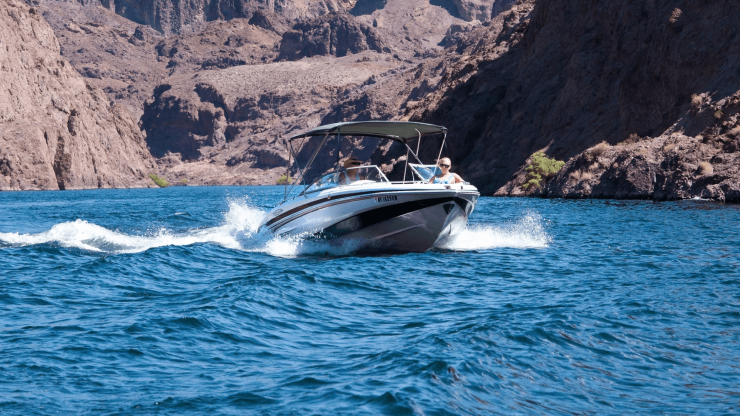 A boat glides through vibrant blue waters, surrounded by rugged cliffs, capturing a moment of adventure.