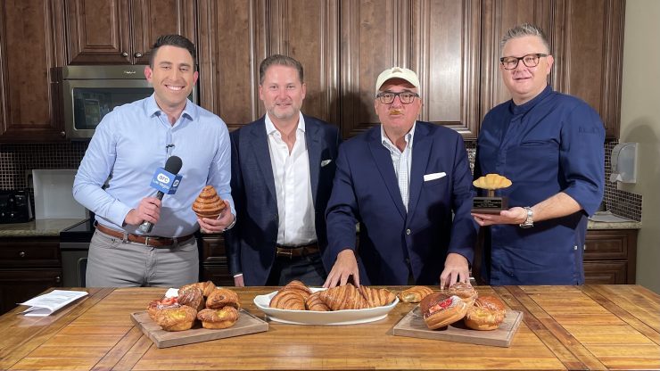 Four professionals gather around a table of pastries, exuding camaraderie and warmth in a welcoming kitchen.