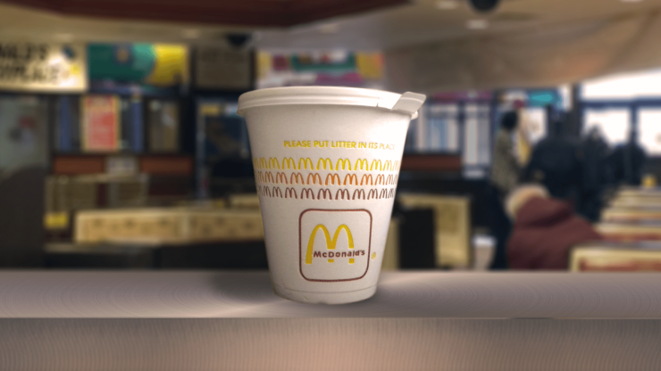 A McDonald's cup stands prominently in a bustling restaurant, reflecting a community atmosphere.