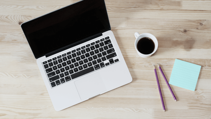 A clean workspace featuring a laptop, coffee, and notepads, exuding professionalism and focus.