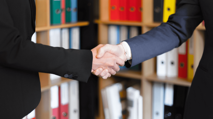A confident handshake in a professional setting conveys trust and mutual commitment.