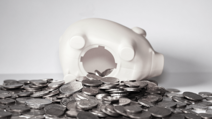 A toppled piggy bank surrounded by scattered coins conveys financial vulnerability and the need for support.