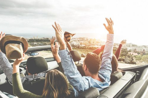 5 people in the car driving with hands in the air