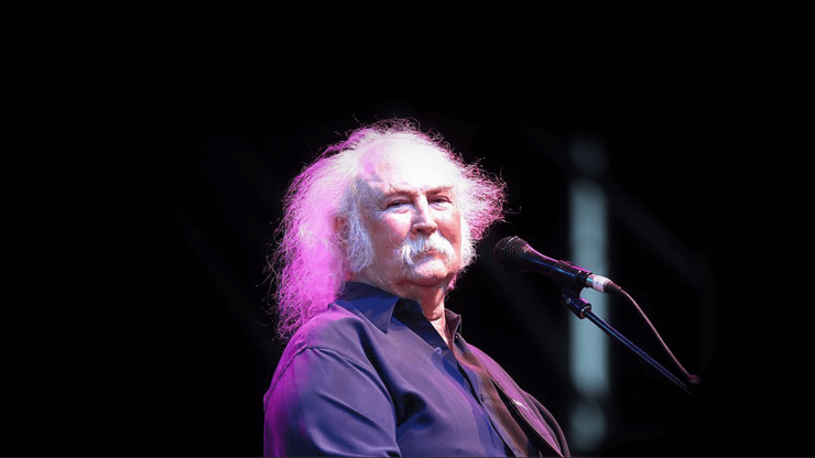 A confident performer engages the audience, illuminated by soft stage lights, evoking a heartfelt atmosphere.