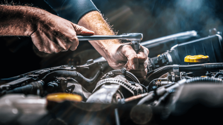 A skilled hand works diligently on a car engine, embodying precision and care in every movement.