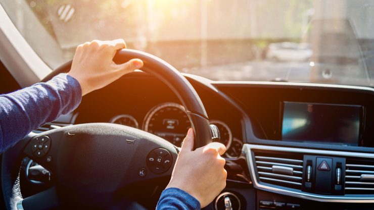 A confident driver navigates the road, embodying focus and responsibility in a sunlit setting.