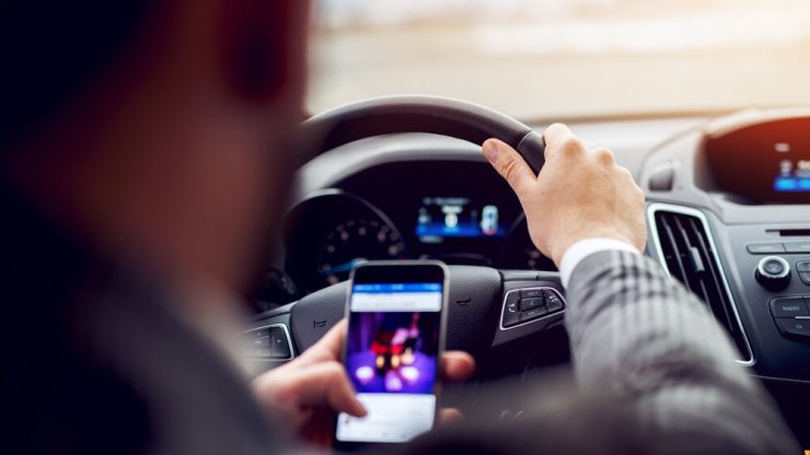 man looking at phone while driving