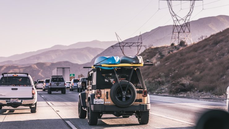Vehicles navigate a busy highway, hinting at the urgency of travel amidst serene mountains, conveying resilience.