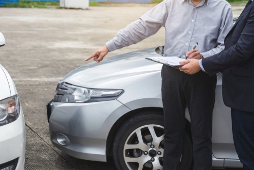 man pointing at his car accident