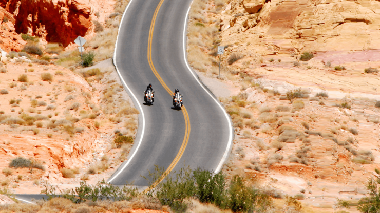 Two motorcyclists navigate a winding road through stunning desert landscapes, evoking freedom and adventure.