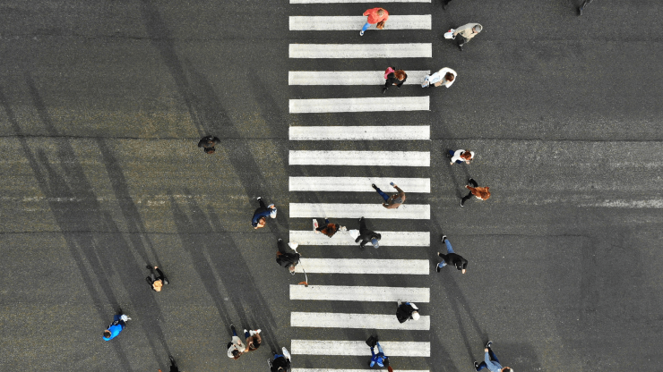 A diverse group of pedestrians confidently crosses a busy intersection, emphasizing community and safety.