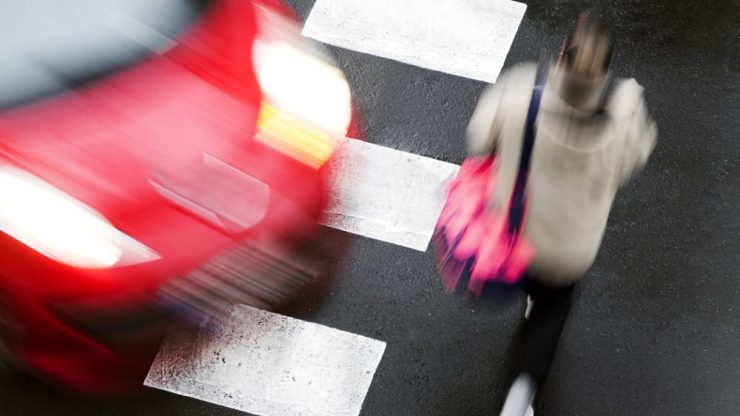A pedestrian crosses a busy street, highlighting the urgency and risks of urban life.
