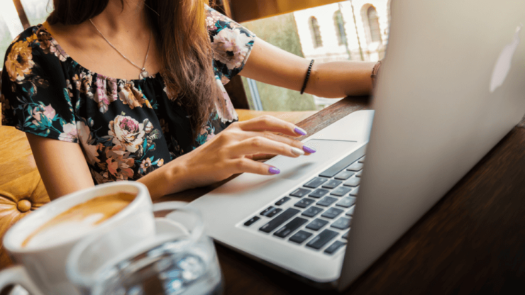 A focused individual engages with their laptop, exuding determination in a welcoming café setting.