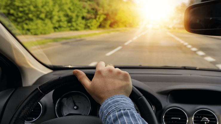 A confident hand grips the steering wheel, guiding the vehicle toward a bright, hopeful horizon.