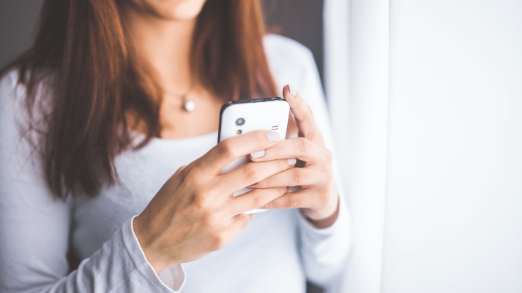 A thoughtful individual engages with their phone, reflecting a moment of connection and support.