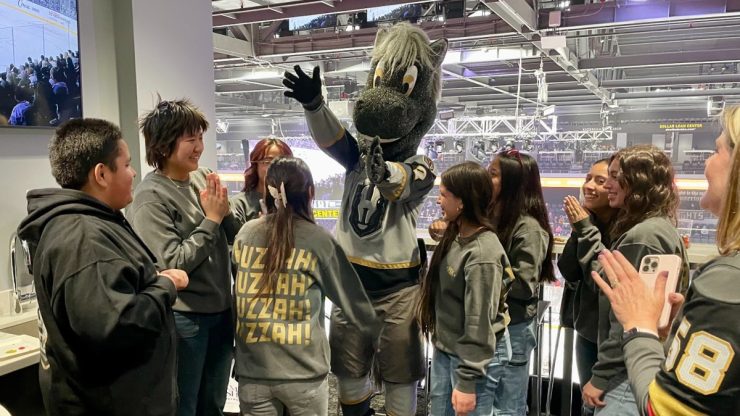 A vibrant gathering of enthusiastic fans enjoys a spirited moment with a mascot, radiating joy and community.