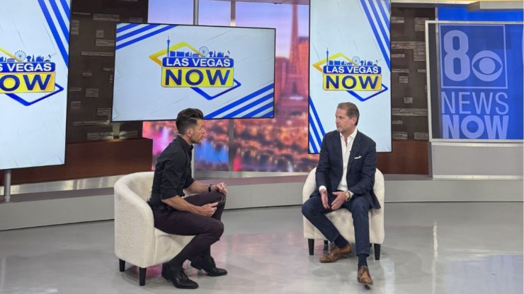 Two professionals engage in a discussion on a modern news set, reflecting confidence and expertise.