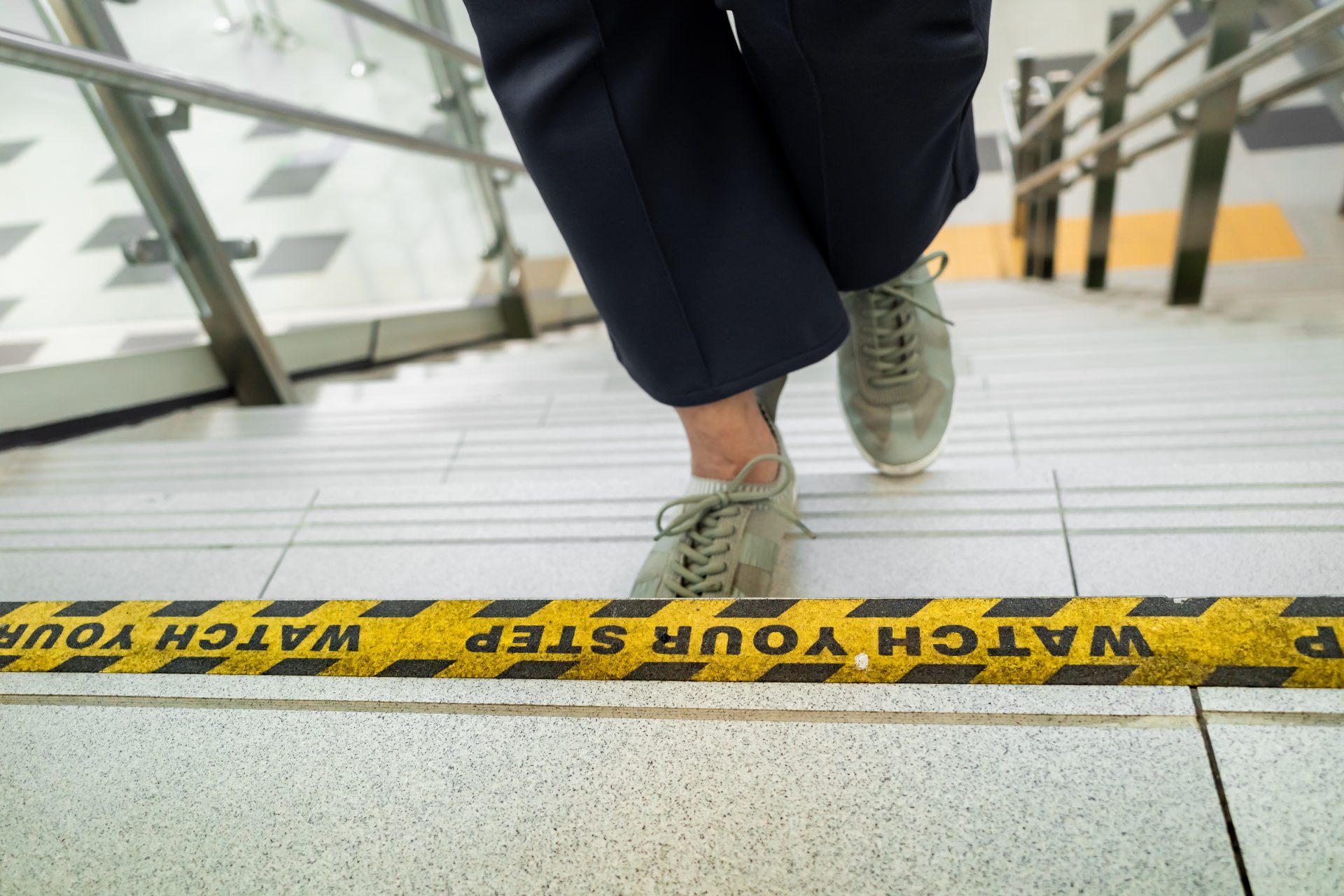 A focused individual carefully navigates stairs marked with a cautionary warning, emphasizing safety.