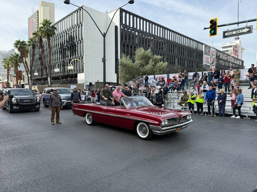 A lively street scene showcases a classic car amidst a cheering crowd, embodying community spirit and celebration.