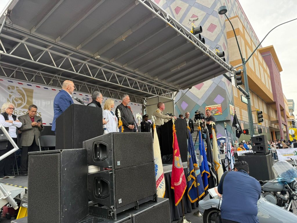 A diverse group gathers on stage, united in purpose, reflecting community strength and resilience.