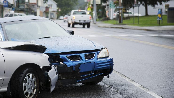 A damaged car sits on a rainy street, symbolizing resilience and the need for compassionate legal support.