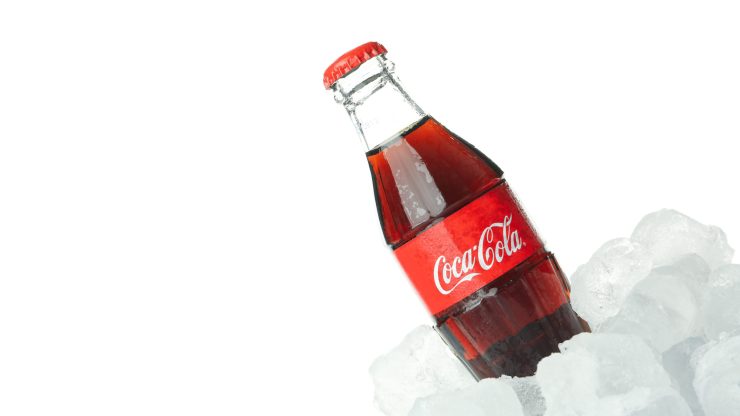 A chilled Coca-Cola bottle rests on ice, symbolizing refreshment and vitality.