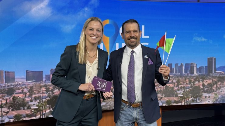 Two confident professionals in business attire smiling in a modern studio with a cityscape backdrop