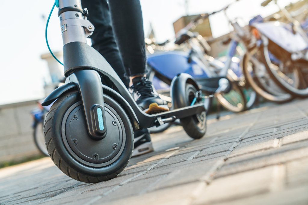 Close-up of a person standing on an electric scooter in an urban setting, emphasizing safety and mobility.