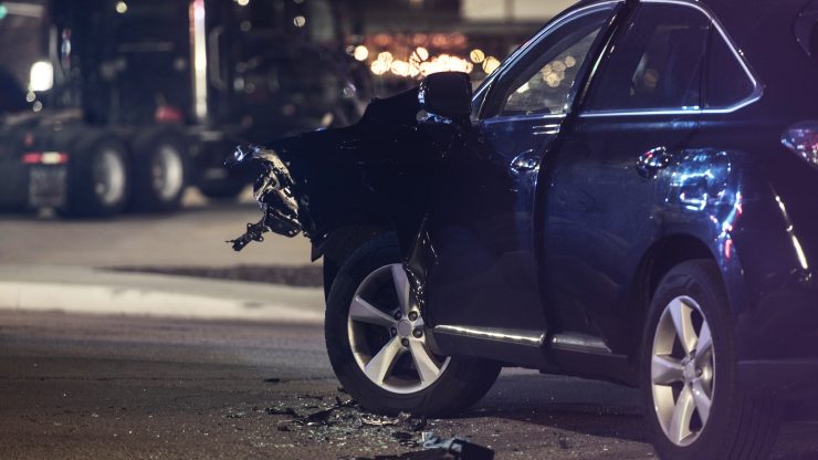 Nighttime collision scene with damaged vehicle and scattered debris on urban street, highlighting urgent legal support.