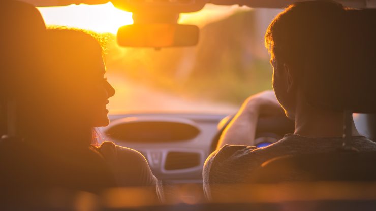 Couple driving during sunset, conveying safety, trust, and support on the road.