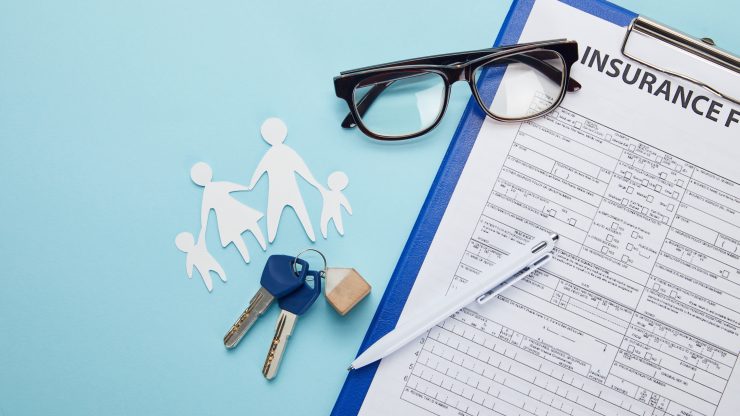 Insurance form with keys, glasses, and paper cutout family symbolizing protection and support.