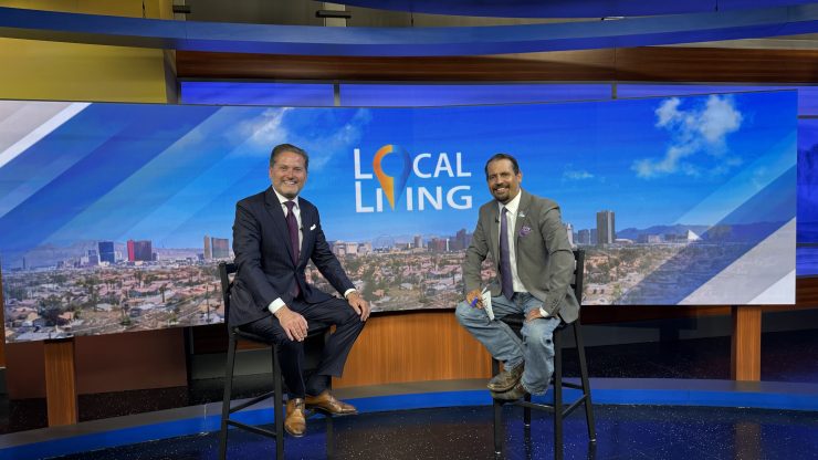Two confident men in suits seated in a professional studio setting with Local Living backdrop