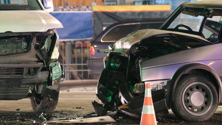 Severe front-end collision between two vehicles at a crash scene marked by safety cones.