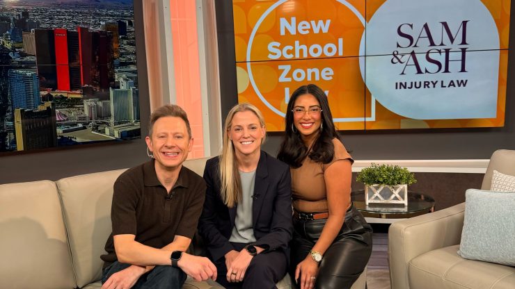 Three professionals seated confidently on a modern set with Sam & Ash Injury Law branding behind them.