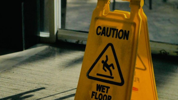 Yellow caution wet floor sign in bright indoor space, highlighting safety warning.